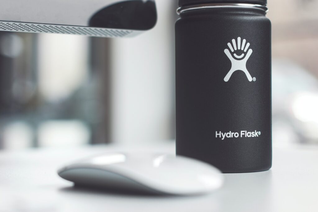 A hydro flask water bottle sits on top a white desk as the perfect work from home accessory